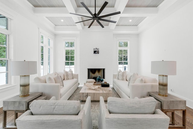 living room featuring coffered ceiling, wood-type flooring, a large fireplace, beamed ceiling, and ceiling fan