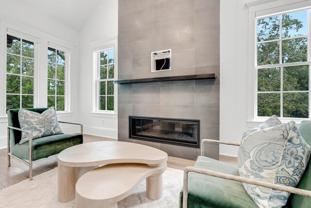 living room featuring hardwood / wood-style flooring, plenty of natural light, tile walls, and a fireplace