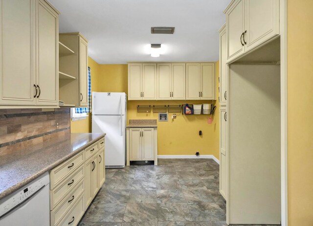 kitchen featuring white appliances, tasteful backsplash, and dark tile flooring