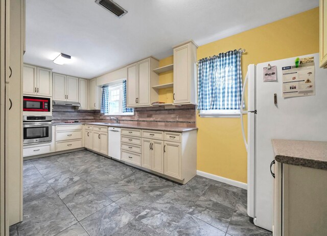 kitchen with white appliances, backsplash, and dark tile flooring