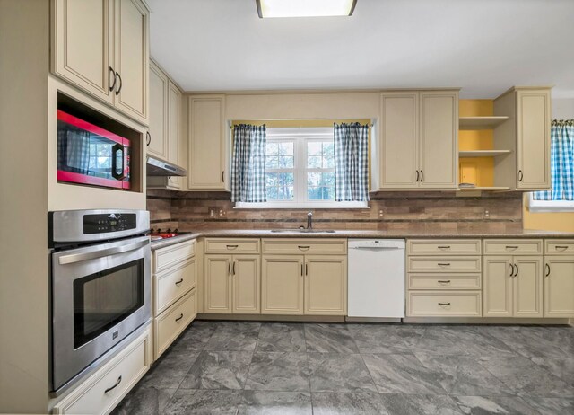 kitchen featuring appliances with stainless steel finishes, plenty of natural light, tasteful backsplash, and dark tile floors