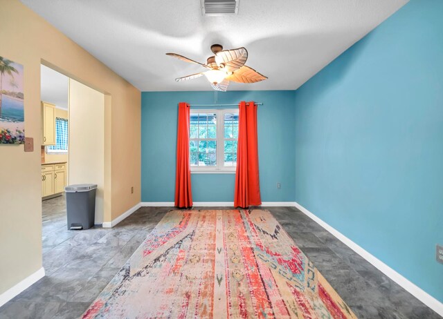 empty room with dark tile flooring and ceiling fan