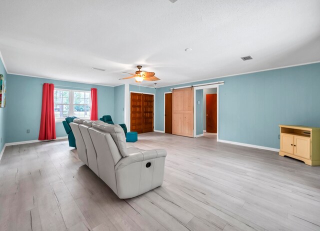 living room with a barn door, ceiling fan, and light hardwood / wood-style flooring