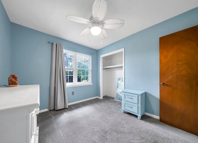 unfurnished bedroom featuring a closet, dark carpet, and ceiling fan