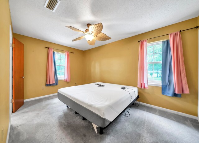 bedroom featuring carpet floors, ceiling fan, and a textured ceiling