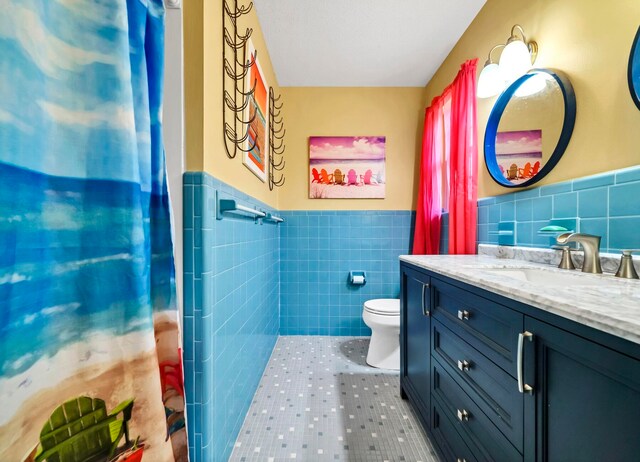 bathroom with tile flooring, oversized vanity, tile walls, and toilet