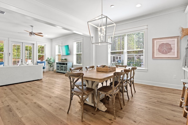 dining room with ceiling fan with notable chandelier, crown molding, light wood-style floors, and baseboards