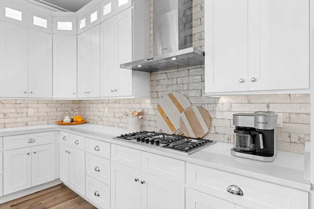 kitchen with white cabinets, wall chimney exhaust hood, light countertops, and stainless steel gas cooktop