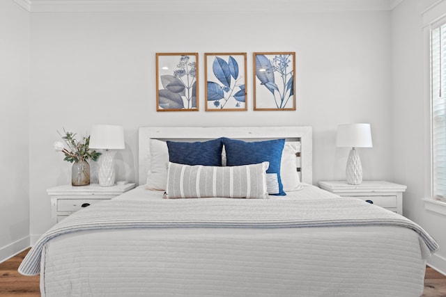 bedroom featuring baseboards, wood finished floors, and crown molding