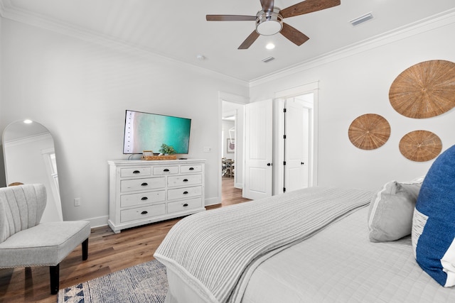 bedroom with crown molding, wood finished floors, and visible vents