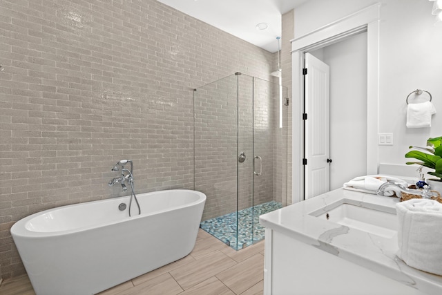 bathroom featuring double vanity, a shower stall, a freestanding tub, and a sink