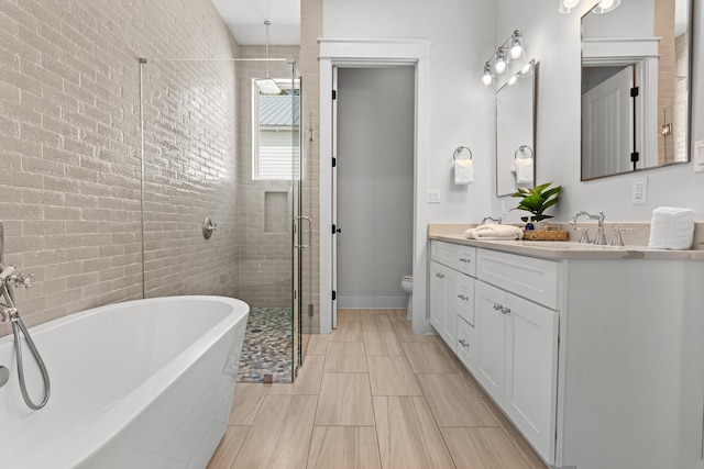 bathroom featuring toilet, a stall shower, a sink, double vanity, and a soaking tub