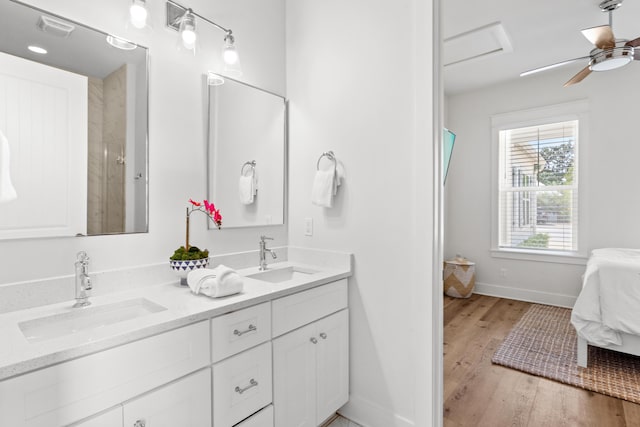 ensuite bathroom featuring a sink, baseboards, wood finished floors, and ensuite bath