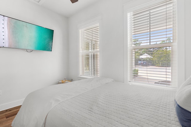 bedroom featuring baseboards, wood finished floors, and a ceiling fan