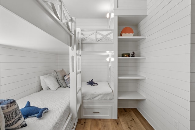 bedroom with light wood-type flooring and wooden walls