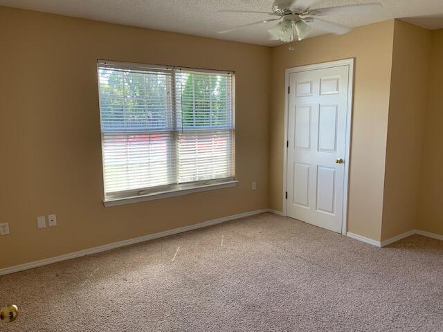 unfurnished bedroom with ceiling fan, a textured ceiling, and carpet flooring