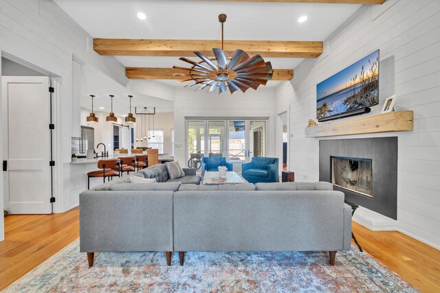 living room featuring sink, vaulted ceiling with beams, light wood-type flooring, and french doors