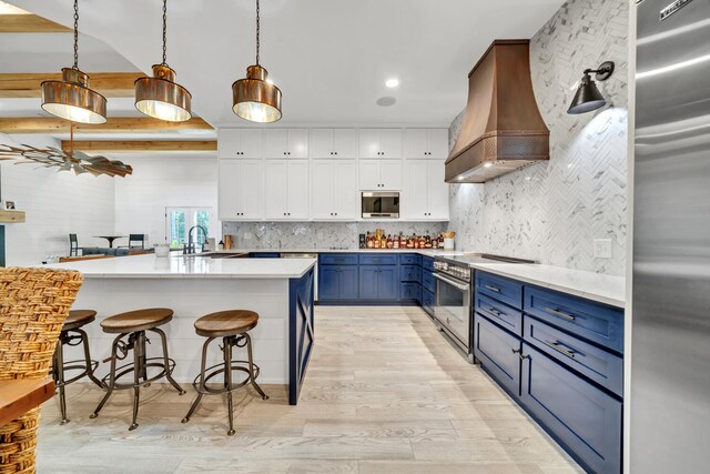 kitchen with tasteful backsplash, white cabinetry, blue cabinetry, premium range hood, and built in appliances