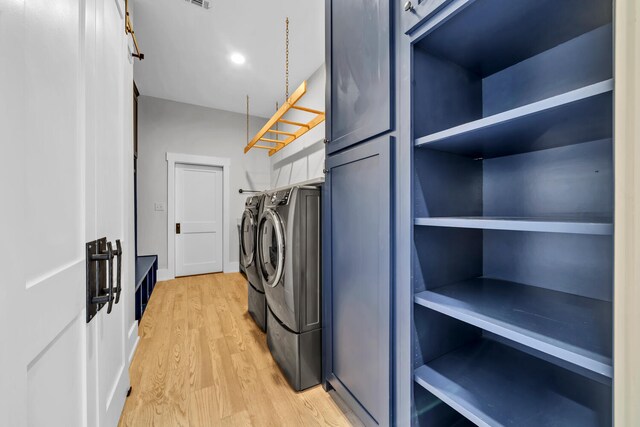 washroom featuring light hardwood / wood-style flooring, cabinets, and washer and clothes dryer