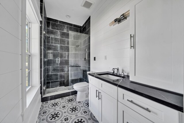 bathroom featuring plenty of natural light, an enclosed shower, toilet, and tile flooring