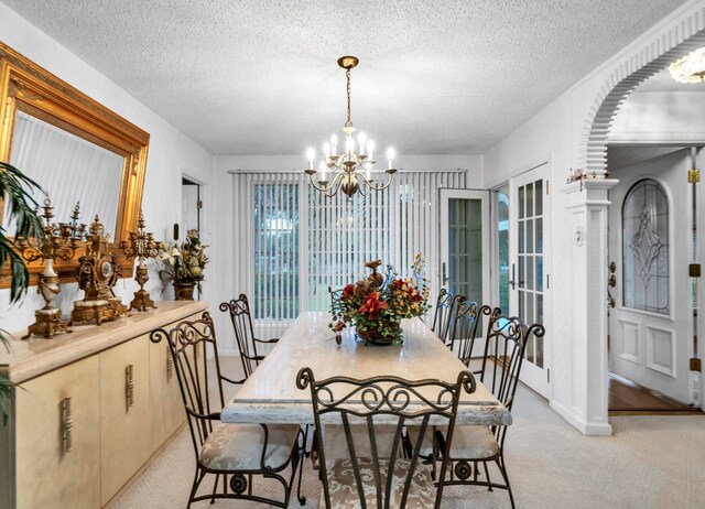 dining area with light carpet, a textured ceiling, and an inviting chandelier