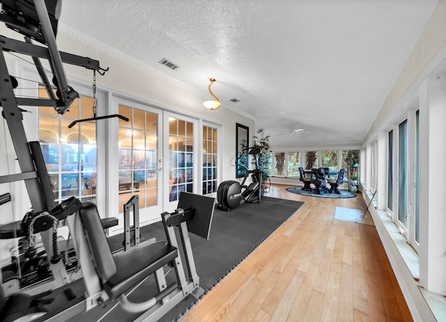 exercise room featuring a textured ceiling, french doors, and hardwood / wood-style flooring