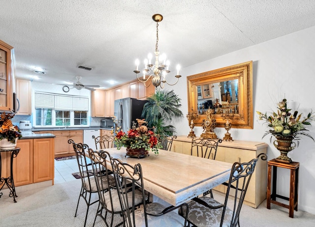 dining area with ceiling fan with notable chandelier, light colored carpet, and a textured ceiling