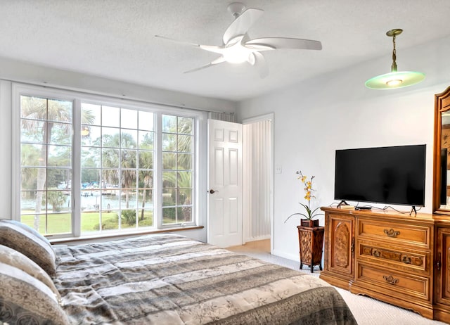 carpeted bedroom with a textured ceiling, ceiling fan, and multiple windows