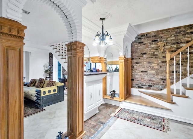 entryway featuring a chandelier, tile floors, brick wall, and a textured ceiling