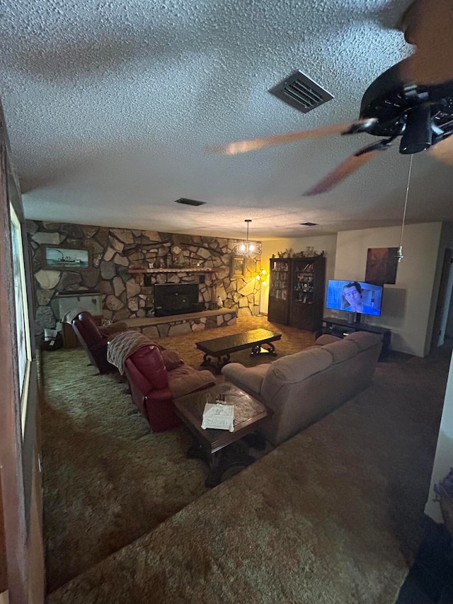 carpeted living room with ceiling fan with notable chandelier, a textured ceiling, and a fireplace