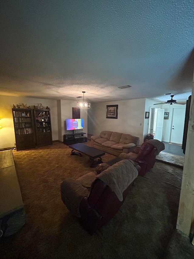 living room with ceiling fan with notable chandelier, a textured ceiling, and carpet