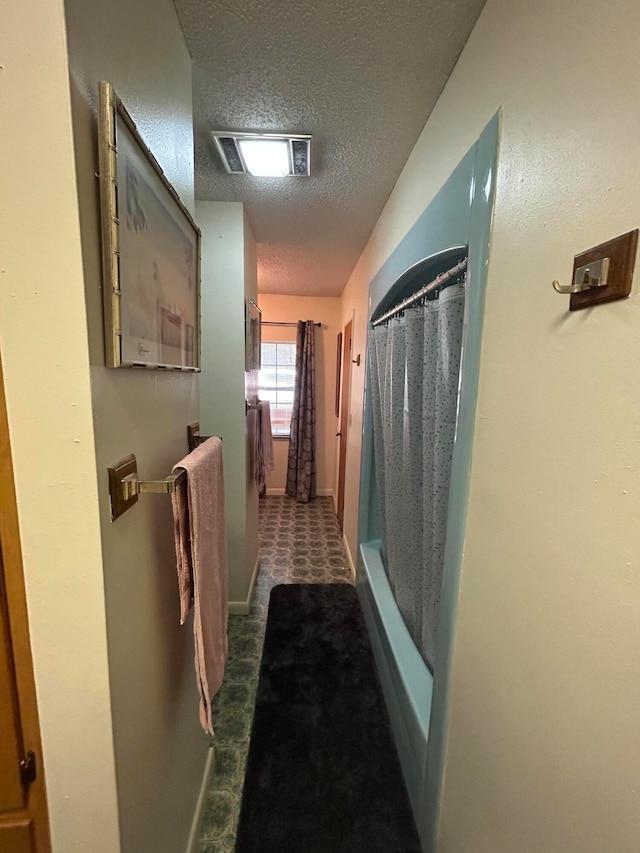 hall featuring a textured ceiling