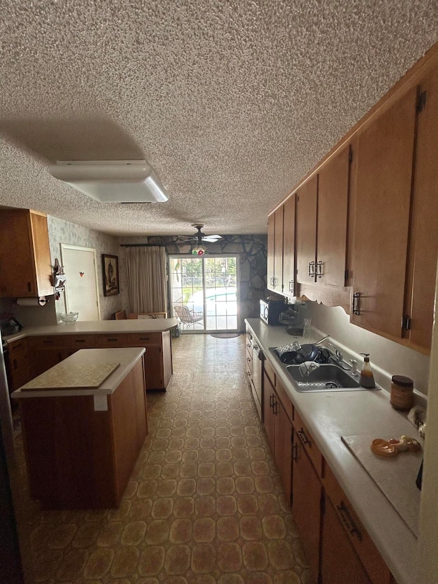 kitchen with a center island, dark tile floors, sink, ceiling fan, and a textured ceiling