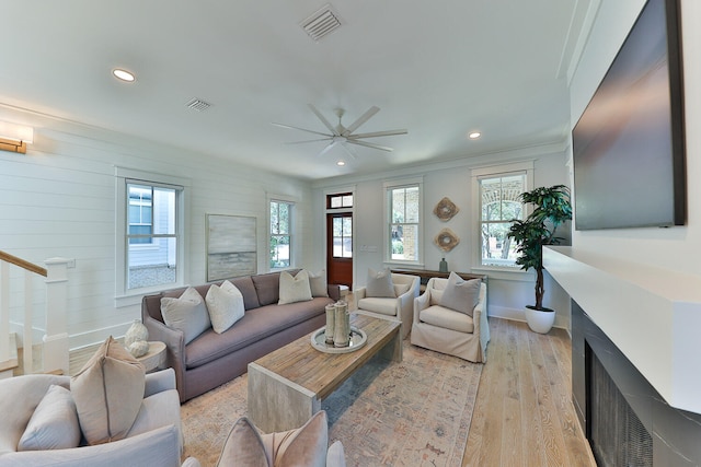 living room featuring ceiling fan, crown molding, and light wood-type flooring