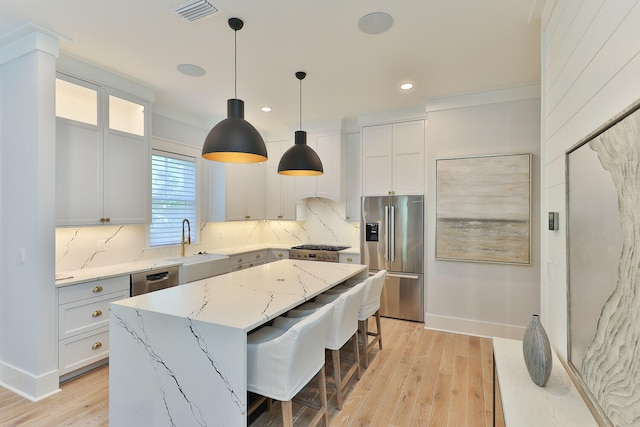 kitchen featuring appliances with stainless steel finishes, light hardwood / wood-style floors, a center island, and backsplash