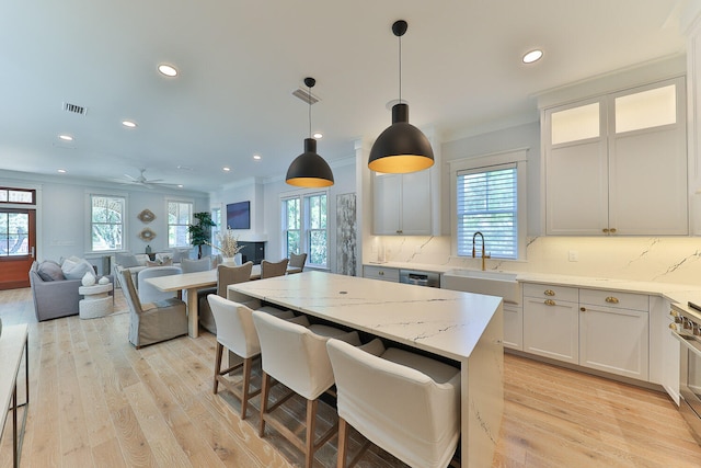 kitchen with backsplash, light hardwood / wood-style flooring, ceiling fan, and a healthy amount of sunlight