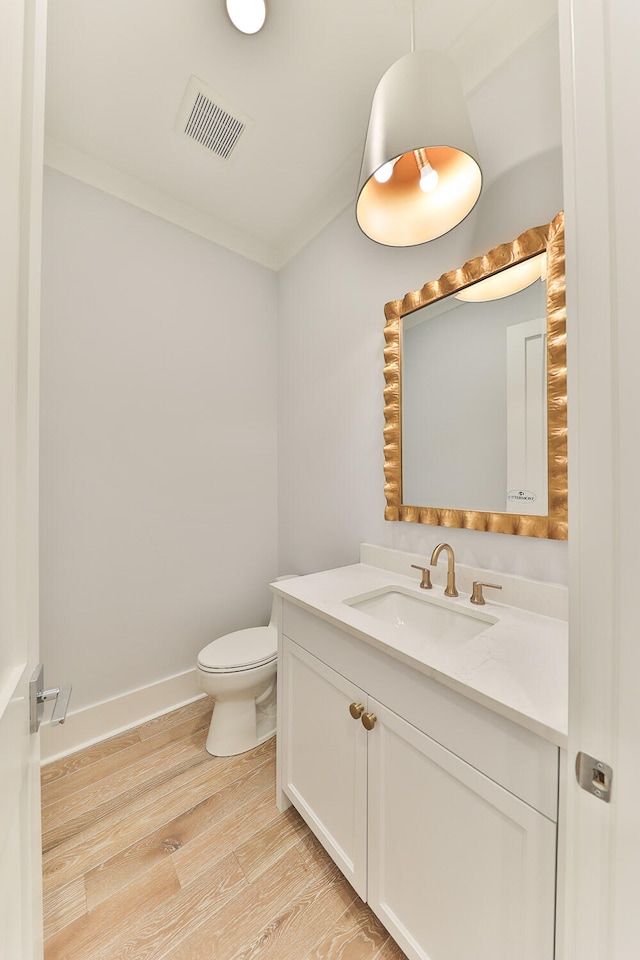 bathroom featuring hardwood / wood-style flooring, crown molding, toilet, and vanity