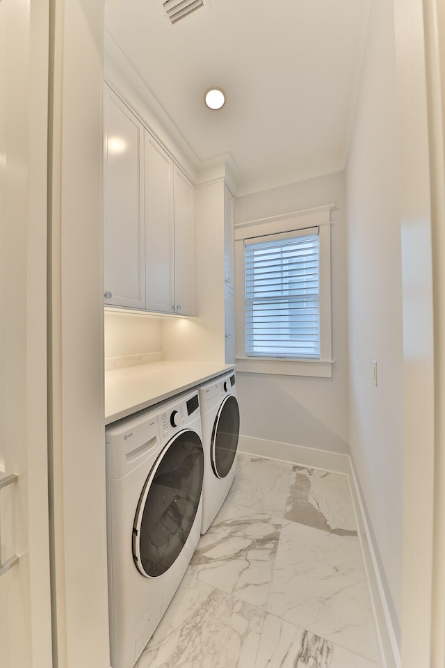 laundry area featuring washing machine and dryer, light tile flooring, and cabinets