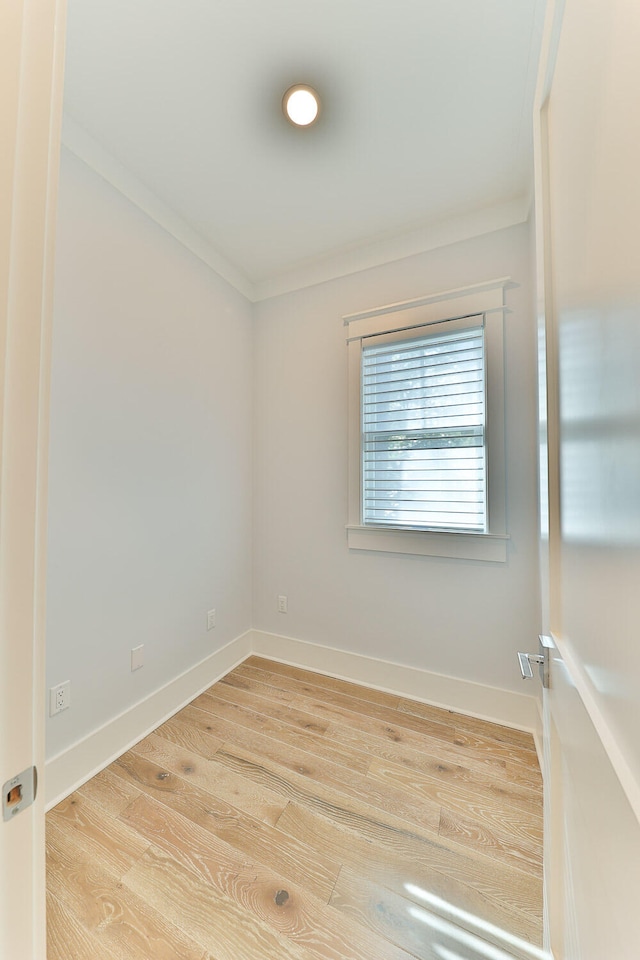 spare room with ornamental molding and light hardwood / wood-style flooring