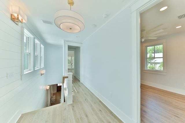 hallway with light hardwood / wood-style floors and crown molding