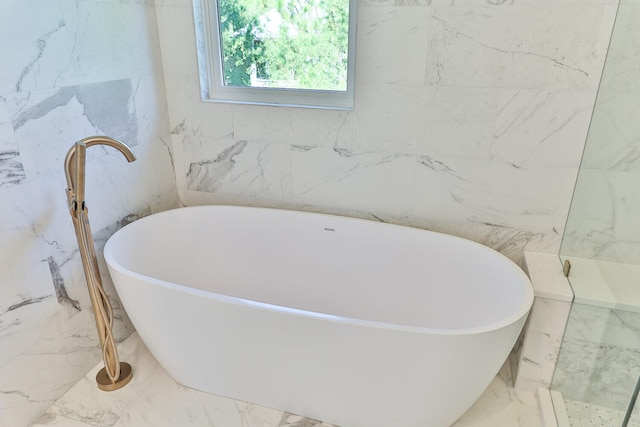 bathroom featuring tile walls, a bath, and tile flooring