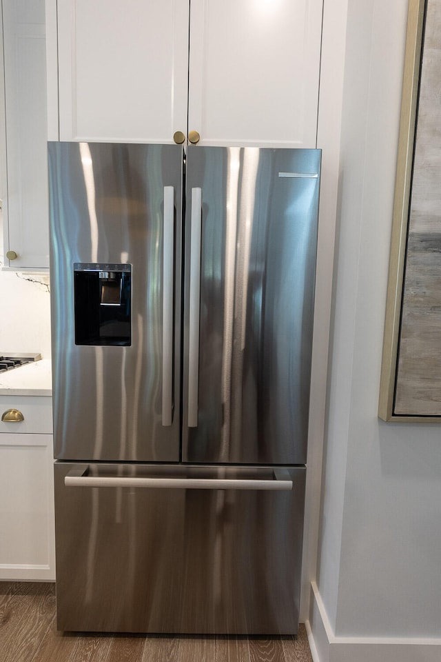 room details featuring wood-type flooring and stainless steel fridge