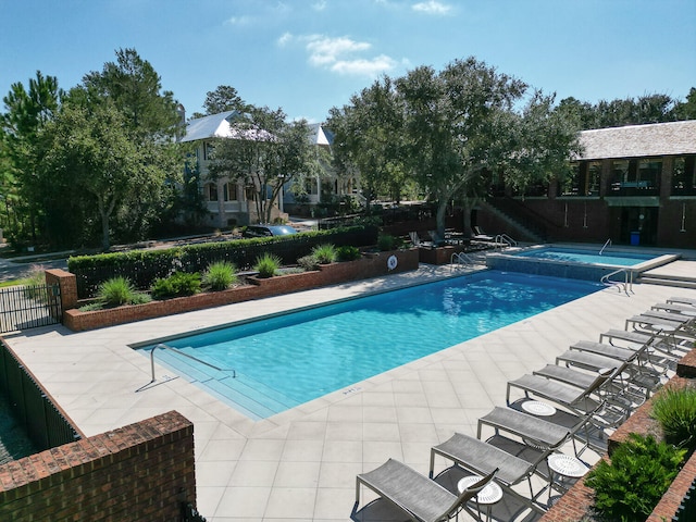 view of swimming pool featuring a hot tub and a patio area