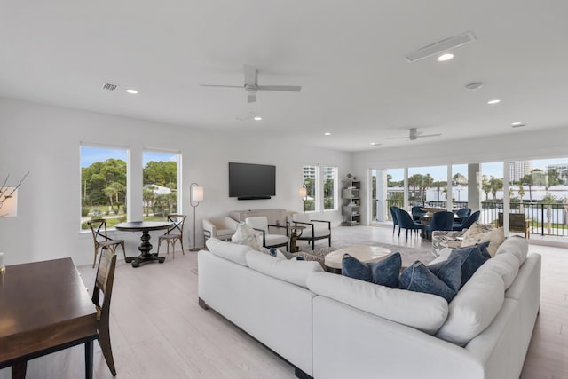 living room with ceiling fan, light wood-type flooring, and plenty of natural light