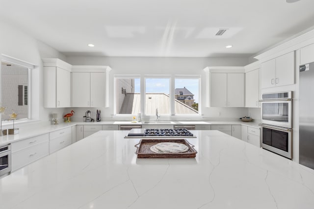 kitchen featuring white cabinets, sink, stainless steel appliances, and light stone countertops