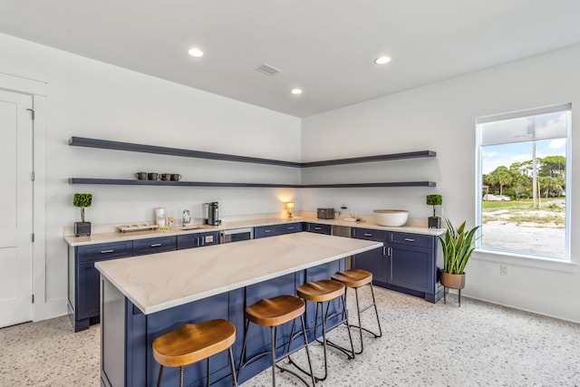 kitchen with blue cabinets, a breakfast bar area, and light stone countertops