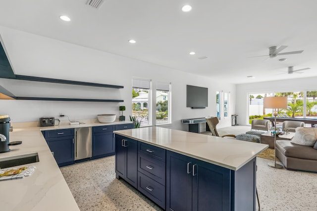 kitchen with blue cabinetry, ceiling fan, dishwasher, light stone counters, and a center island