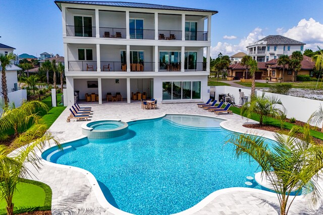 rear view of property with a patio area, a balcony, and a pool with hot tub