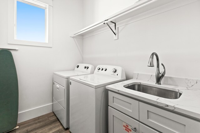 washroom with washer and clothes dryer, dark hardwood / wood-style flooring, cabinets, and sink