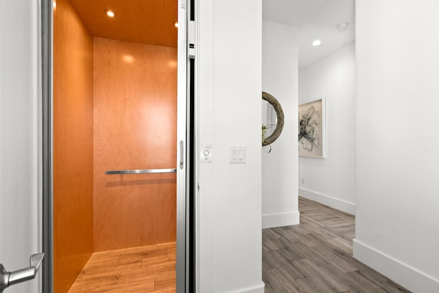 hallway featuring wood-type flooring and elevator